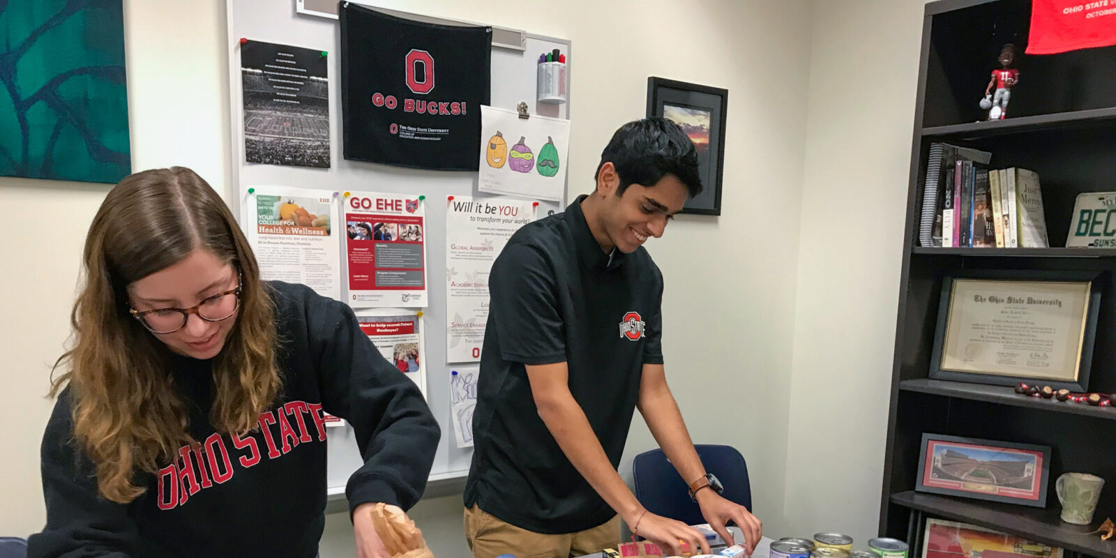 Two Ohio State students arrange food on a table for the college's food pantry