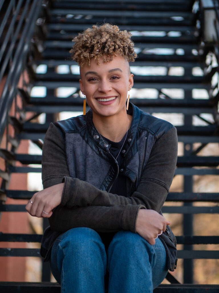 Olivia Small sits on a metal staircase resting her arms across her lap