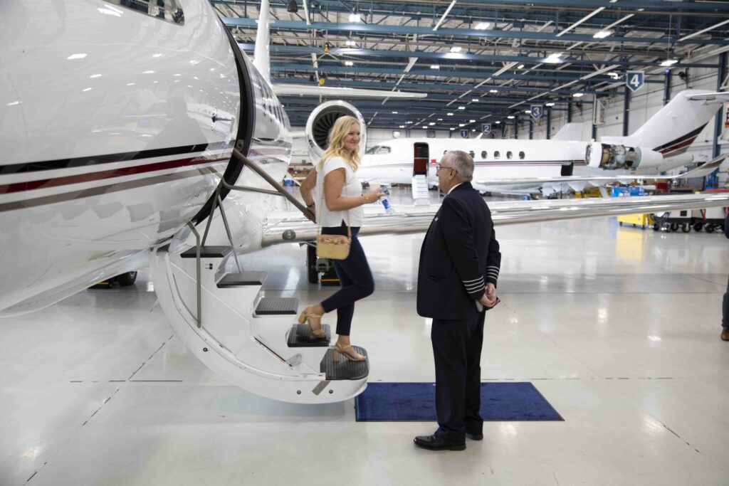 Woman walking off NetJets airplane in hanger with pilot