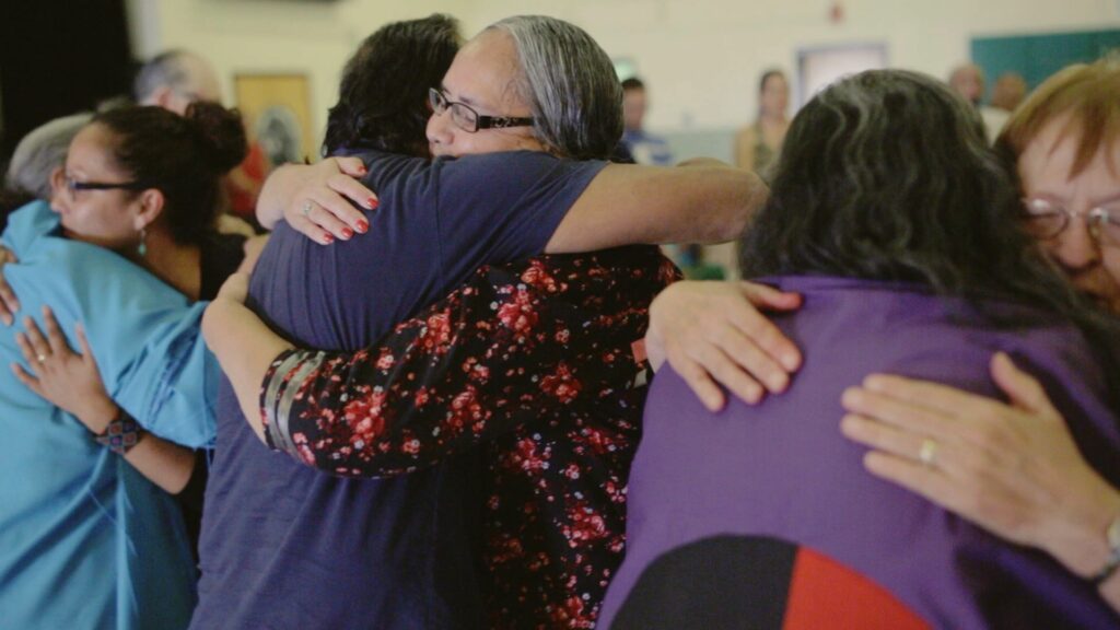 Sandy White Hawk and group hugging at reunion