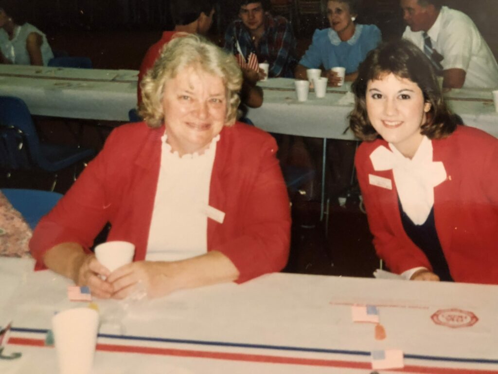 Two women at event table in red jackets