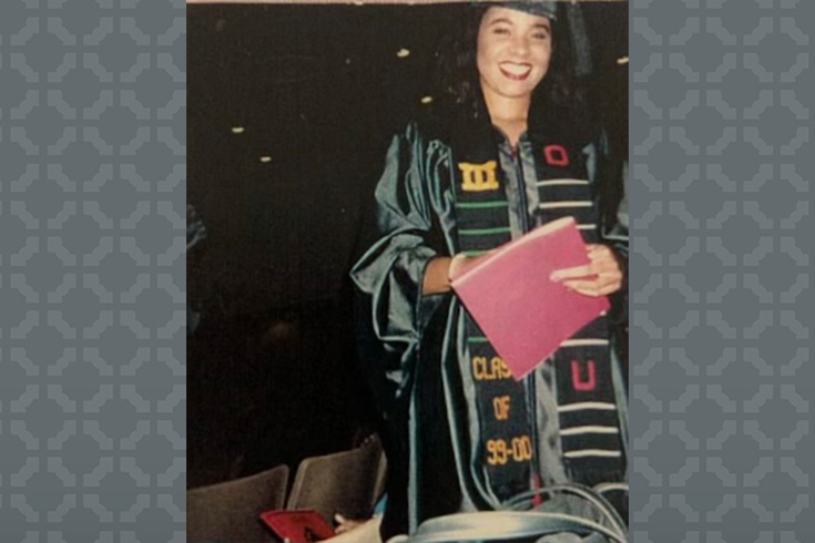 Tasha Lewis in graduation robes hiolding diploma