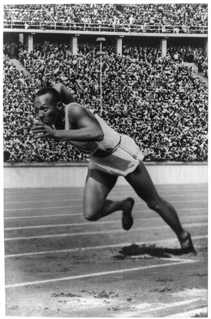 Jesse Owens in a black and white photo running on the track