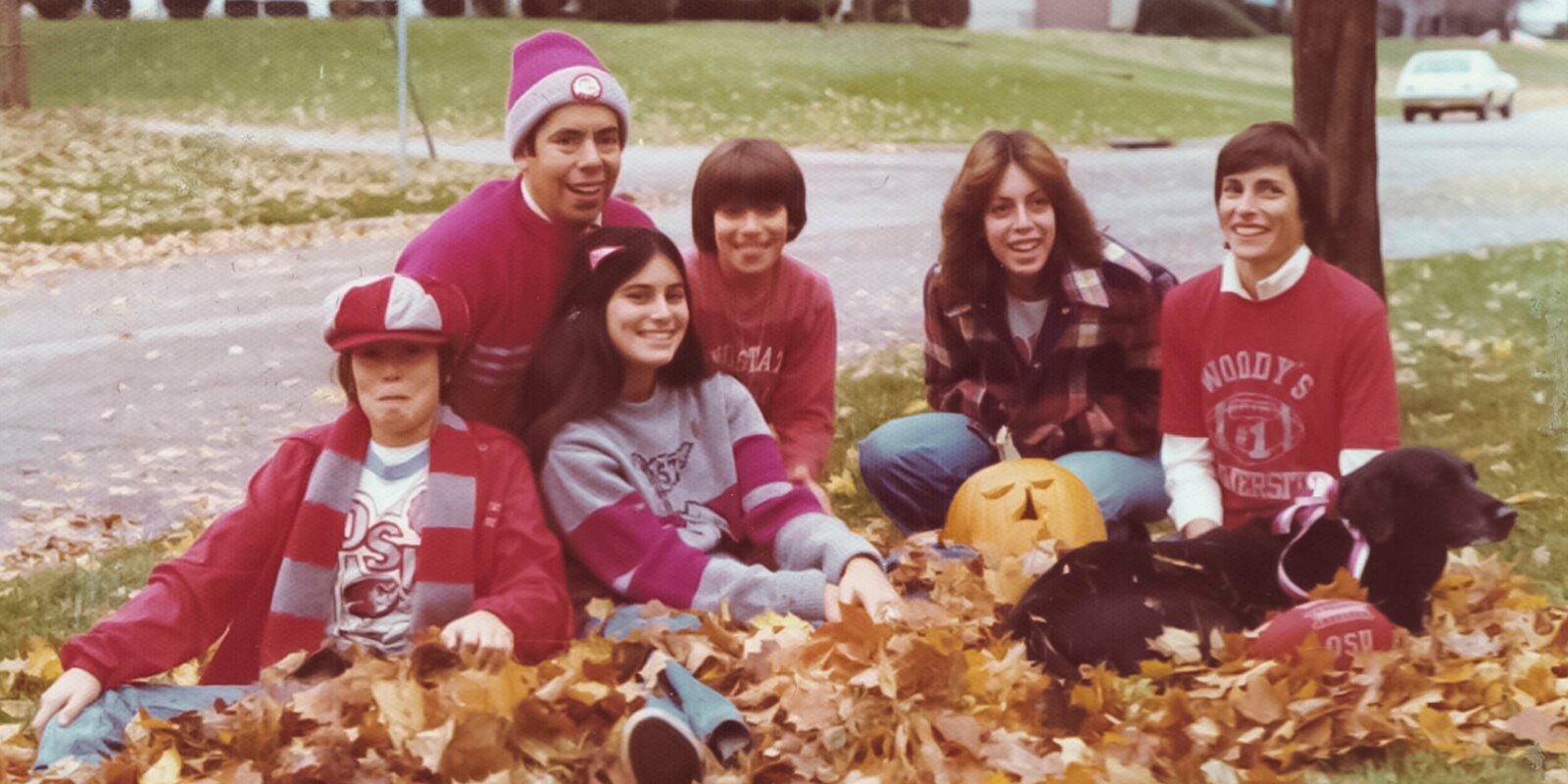 Weiler family photo sitting in leaves in the yard wearing Ohio State clothing.