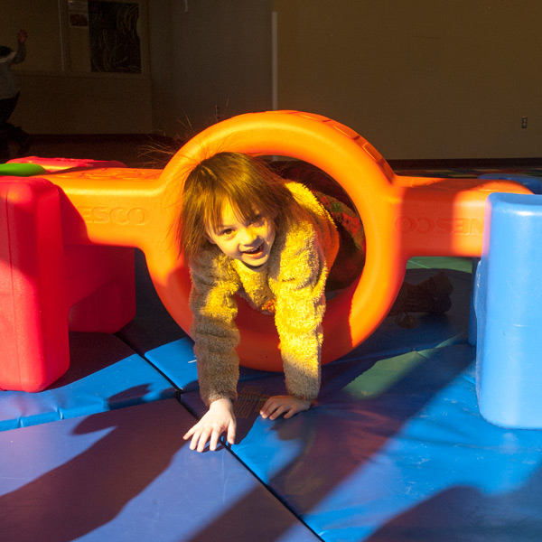Girl playing on blue mat and plastic playground equipment