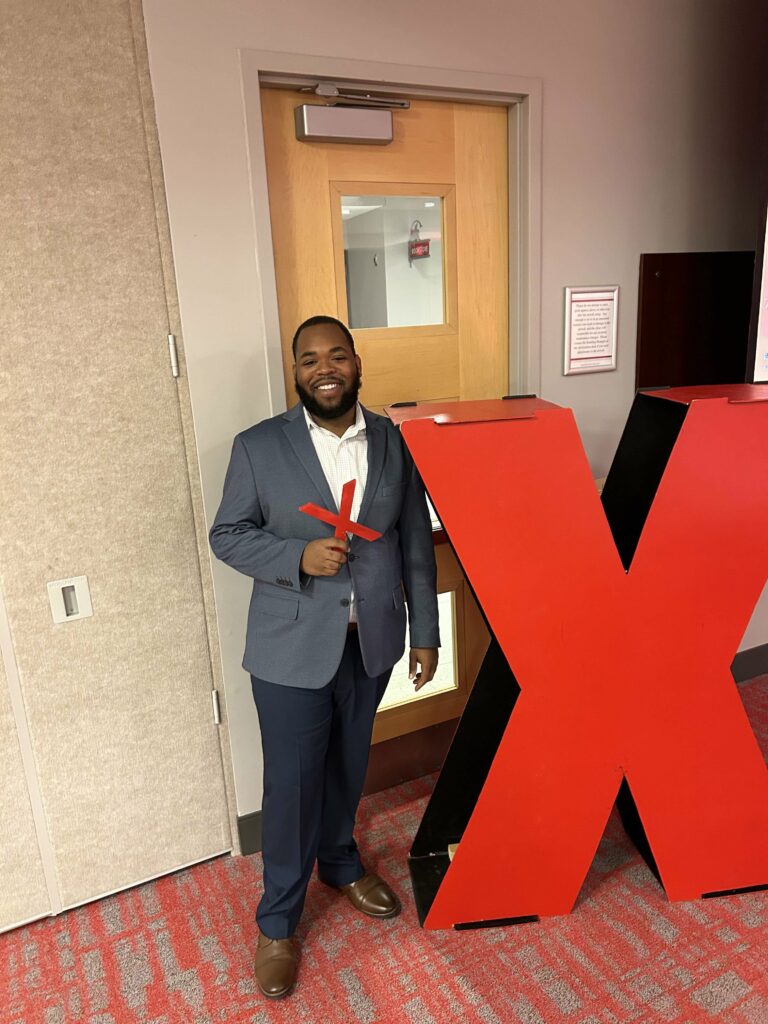 John Fuller standing next to the TedTalk "X"