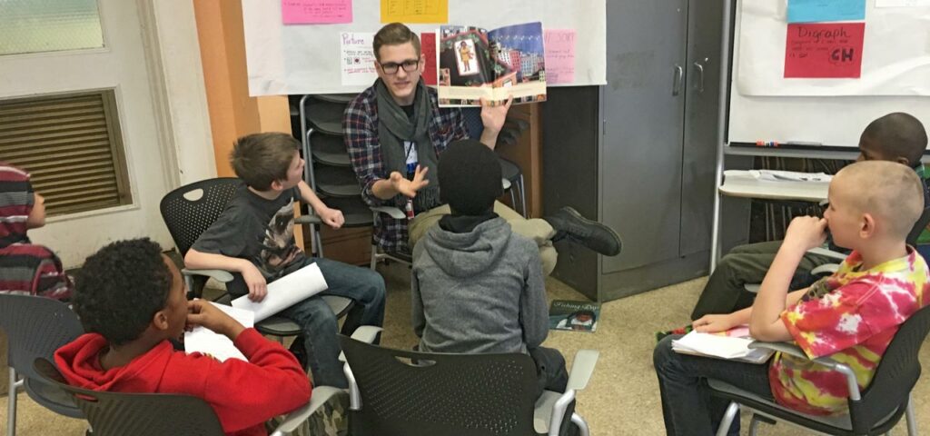 Teacher reading a picture book to a group of young students in a classroom