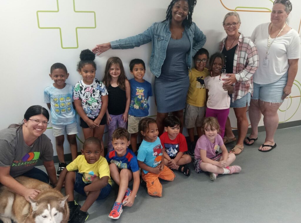 Gina Ginn sitting with a group of young students and teachers during an Early Learning Centers event