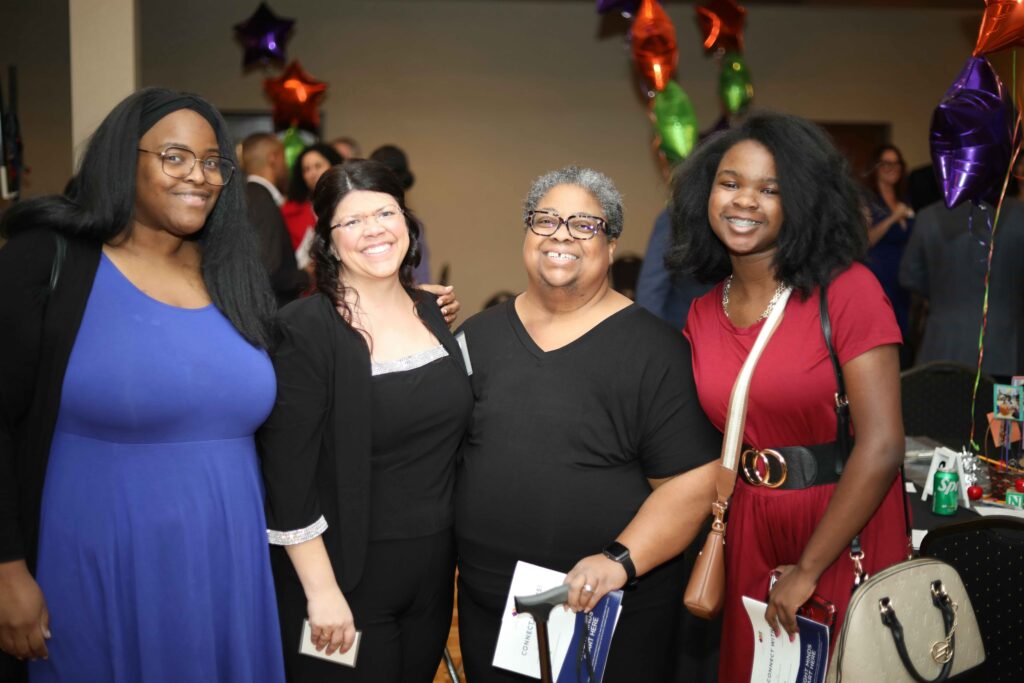 Gina Ginn posing with parents and a student during a gala celebration
