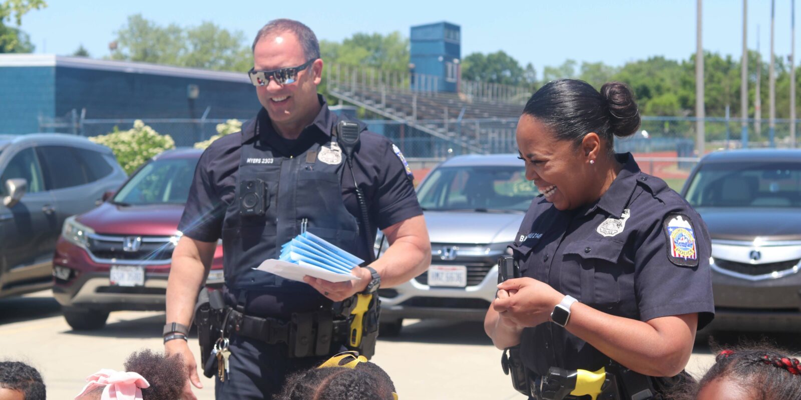 Police officers talking to a group of school age children in a parking lot on a sunny day