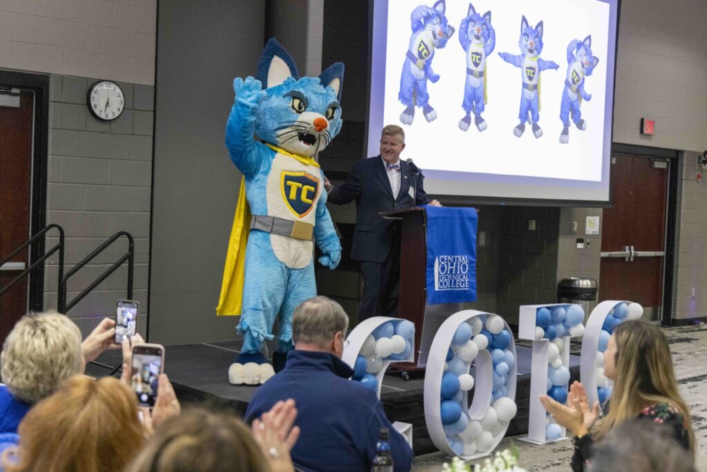 Central Ohio Technical College blue cat mascot and John Berry on stage