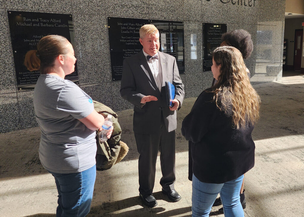 John Berry speaking with students on campus outside academic building