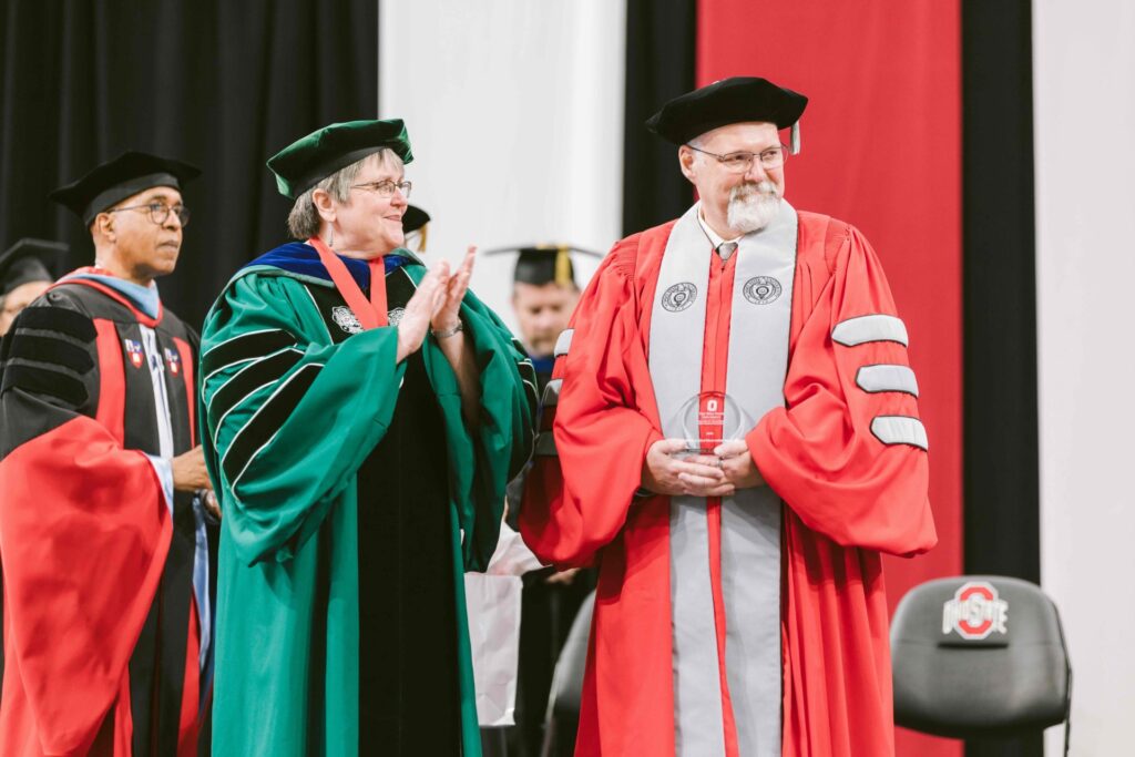 Derek Lee in Ohio State scarlet regalia receiving award during graduation ceremony